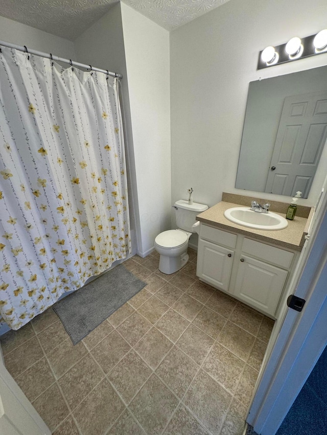 bathroom featuring vanity, toilet, tile patterned flooring, and a textured ceiling