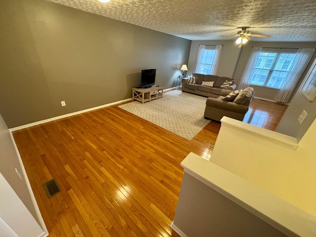 unfurnished living room featuring ceiling fan, wood-type flooring, and a textured ceiling