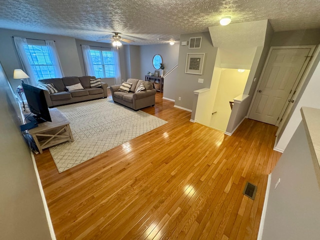 unfurnished living room with ceiling fan, a textured ceiling, and light wood-type flooring