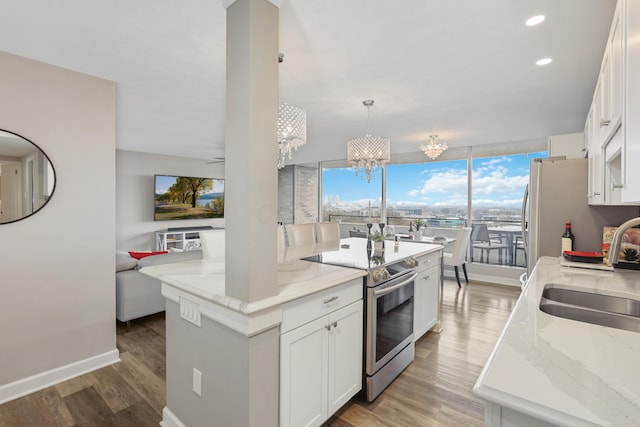 kitchen featuring sink, appliances with stainless steel finishes, white cabinetry, a kitchen island with sink, and hanging light fixtures