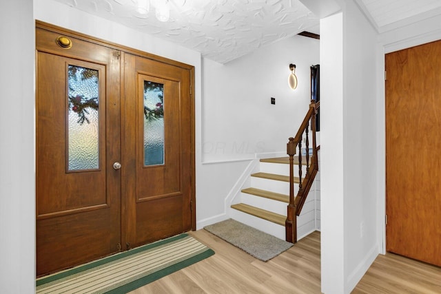 foyer entrance featuring a textured ceiling and light wood-type flooring