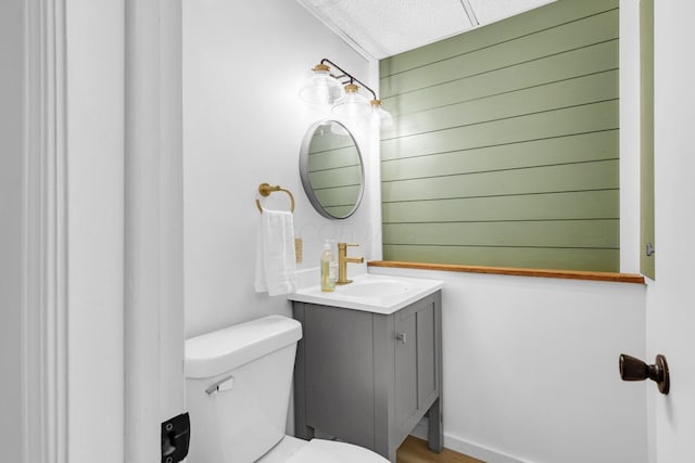 bathroom featuring vanity, toilet, and wood walls