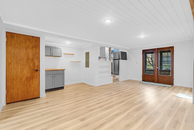 unfurnished living room with ornamental molding, light hardwood / wood-style flooring, electric panel, and french doors