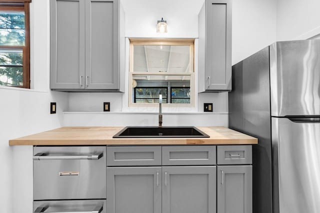 kitchen featuring butcher block counters, sink, gray cabinets, and appliances with stainless steel finishes