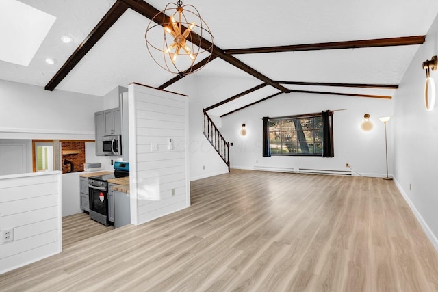 kitchen with gray cabinetry, baseboard heating, appliances with stainless steel finishes, a notable chandelier, and vaulted ceiling with skylight