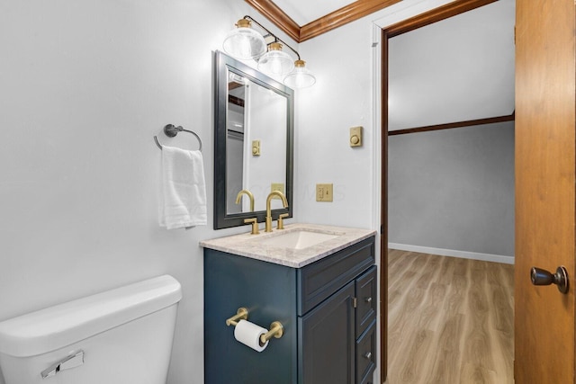 bathroom with ornamental molding, toilet, wood-type flooring, and vanity