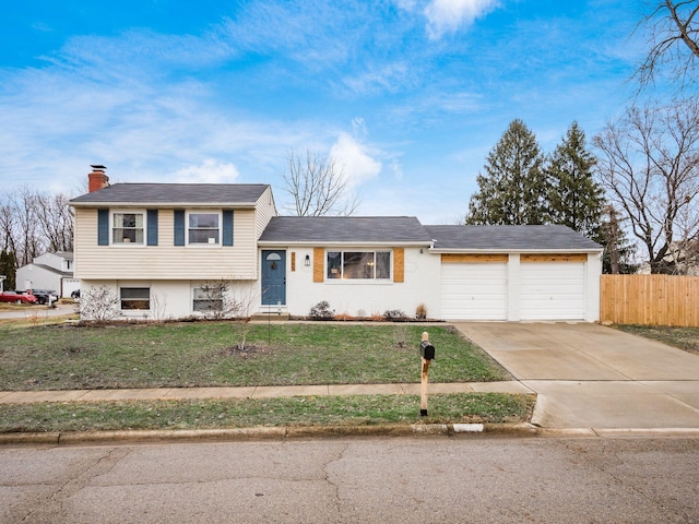 tri-level home featuring a garage and a front lawn