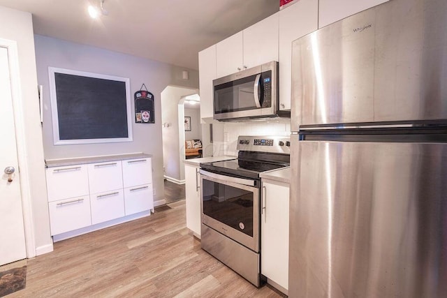 kitchen with stainless steel appliances, light hardwood / wood-style flooring, and white cabinets