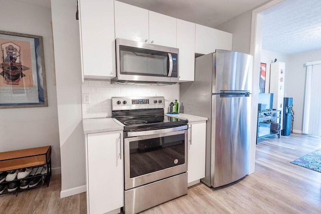 kitchen featuring white cabinetry, backsplash, light hardwood / wood-style flooring, and appliances with stainless steel finishes