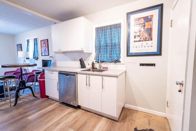 kitchen featuring sink, light wood-type flooring, stainless steel dishwasher, decorative backsplash, and white cabinets