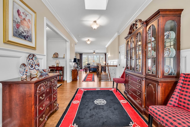 interior space featuring ornamental molding, ceiling fan, light hardwood / wood-style floors, and a skylight