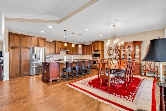 dining room featuring ornamental molding, light hardwood / wood-style flooring, and a notable chandelier