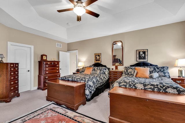 bedroom with a tray ceiling, light colored carpet, and ceiling fan