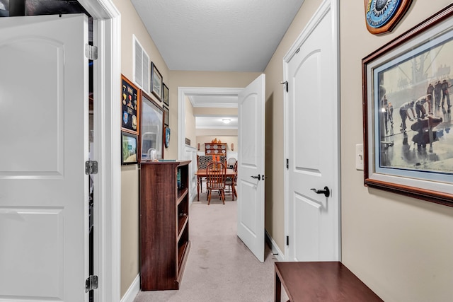 hall with light carpet and a textured ceiling