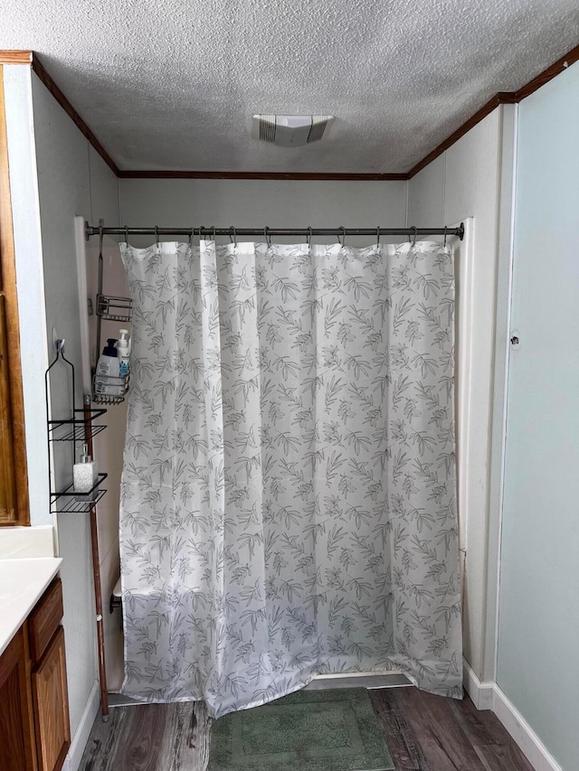 bathroom with vanity, hardwood / wood-style flooring, ornamental molding, and a textured ceiling