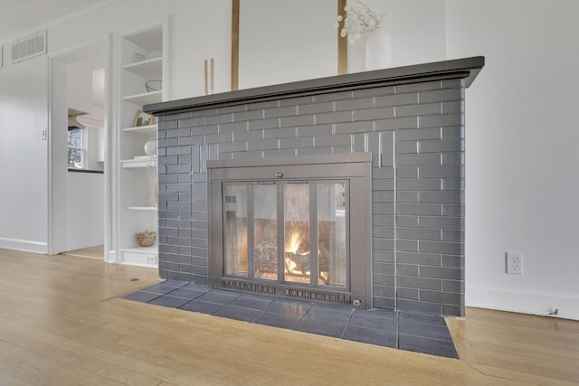 interior details with hardwood / wood-style flooring, a brick fireplace, and built in shelves