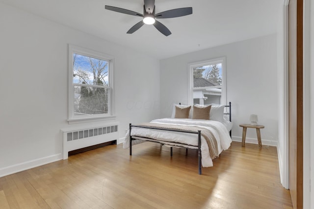 bedroom with radiator, light hardwood / wood-style flooring, and ceiling fan