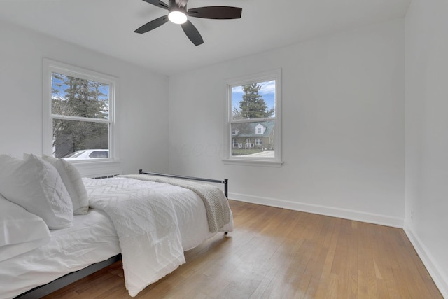 bedroom with multiple windows, light hardwood / wood-style floors, and ceiling fan