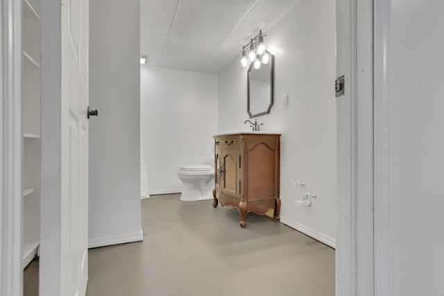 bathroom with concrete flooring, vanity, and toilet