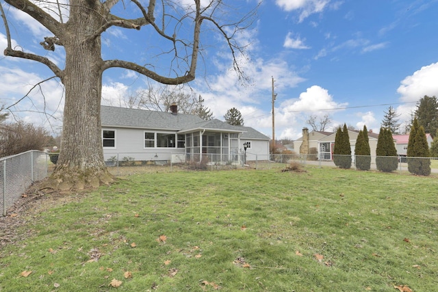 rear view of house featuring a yard and a sunroom