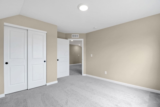 unfurnished bedroom with light colored carpet and a closet