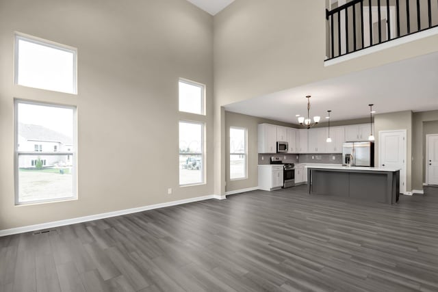 unfurnished living room featuring a towering ceiling, dark hardwood / wood-style floors, and a chandelier