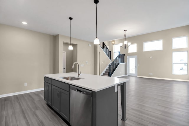 kitchen featuring sink, hanging light fixtures, stainless steel dishwasher, plenty of natural light, and a center island with sink