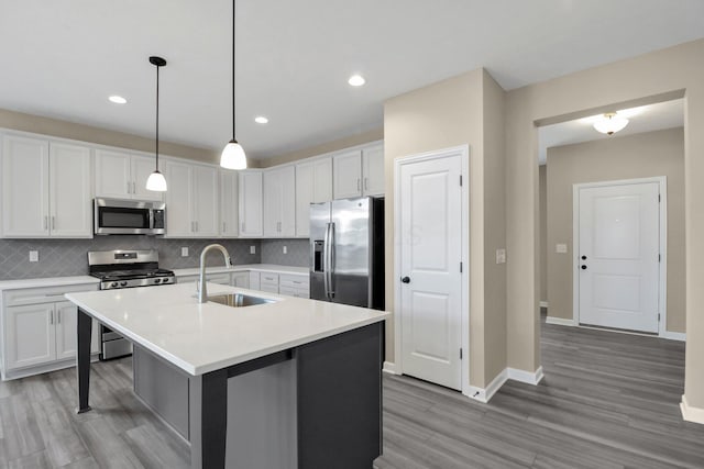 kitchen featuring decorative light fixtures, white cabinetry, sink, a kitchen island with sink, and stainless steel appliances