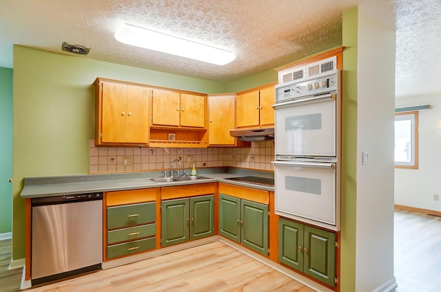 kitchen with double oven, dishwasher, sink, black electric cooktop, and light wood-type flooring