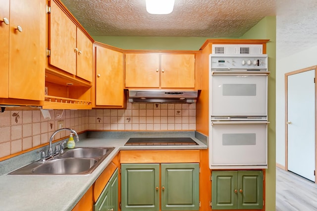 kitchen with double oven, tasteful backsplash, sink, black electric cooktop, and a textured ceiling