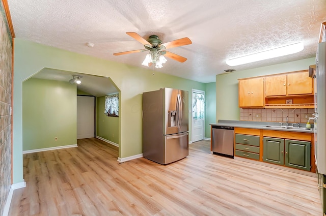 kitchen featuring tasteful backsplash, stainless steel appliances, sink, and light wood-type flooring