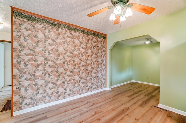 empty room with ceiling fan, hardwood / wood-style floors, and a textured ceiling