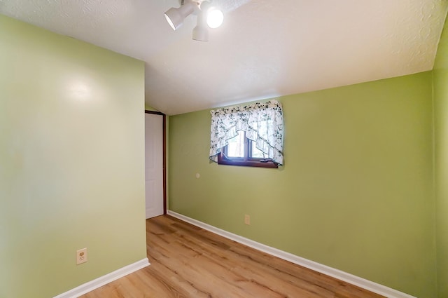 empty room with lofted ceiling and light hardwood / wood-style floors