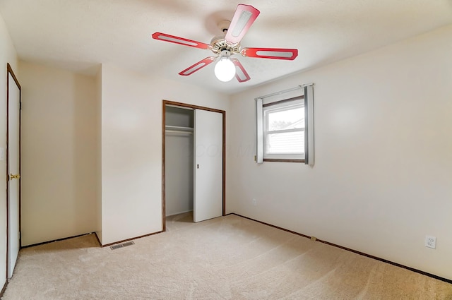 unfurnished bedroom featuring ceiling fan, a closet, and light carpet