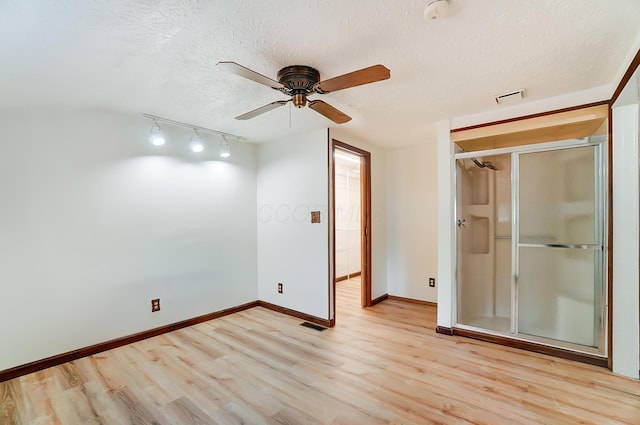 spare room with ceiling fan, track lighting, a textured ceiling, and light wood-type flooring