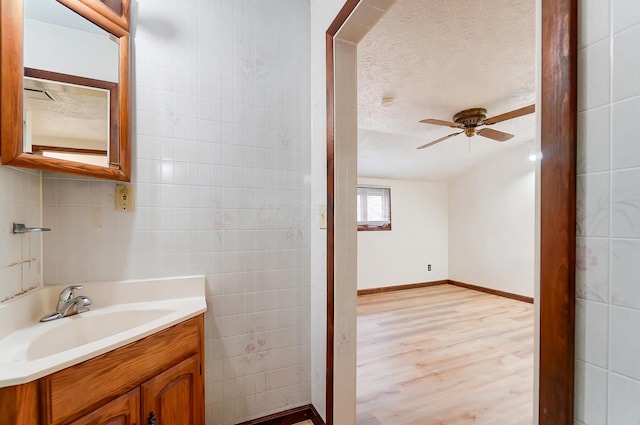 bathroom with vanity, wood-type flooring, tile walls, and a textured ceiling