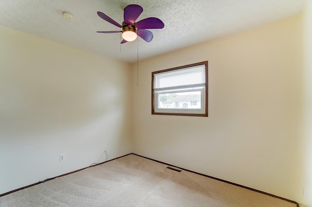 carpeted spare room featuring ceiling fan and a textured ceiling