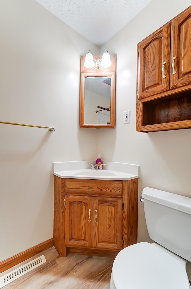 bathroom with hardwood / wood-style flooring, vanity, a textured ceiling, and toilet