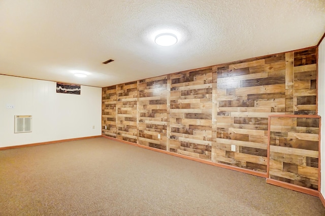 basement featuring wooden walls, carpet floors, and a textured ceiling