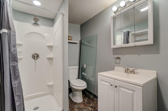 bathroom featuring toilet, vanity, and walk in shower