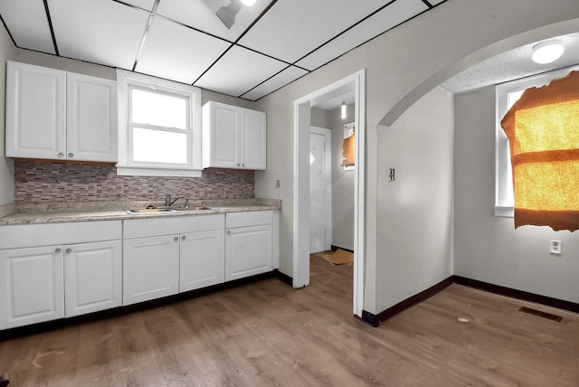 kitchen featuring tasteful backsplash, sink, wood-type flooring, and white cabinets