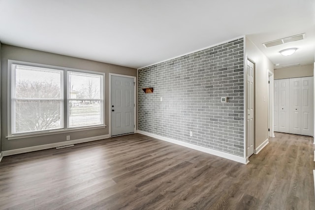 unfurnished room featuring brick wall and hardwood / wood-style floors