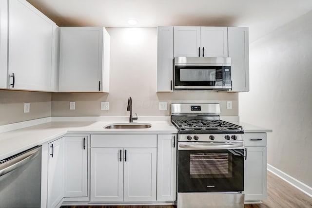 kitchen with white cabinetry, sink, light wood-type flooring, and appliances with stainless steel finishes