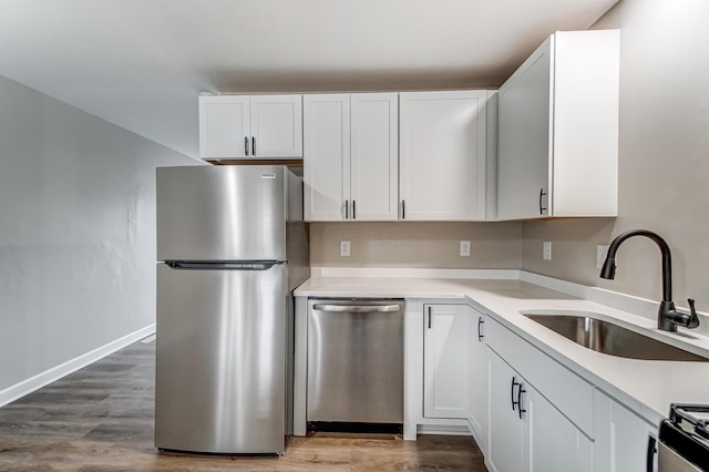 kitchen featuring stainless steel appliances, sink, hardwood / wood-style floors, and white cabinets