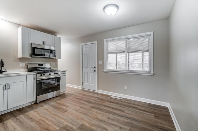 kitchen with white cabinetry, sink, light hardwood / wood-style floors, and appliances with stainless steel finishes