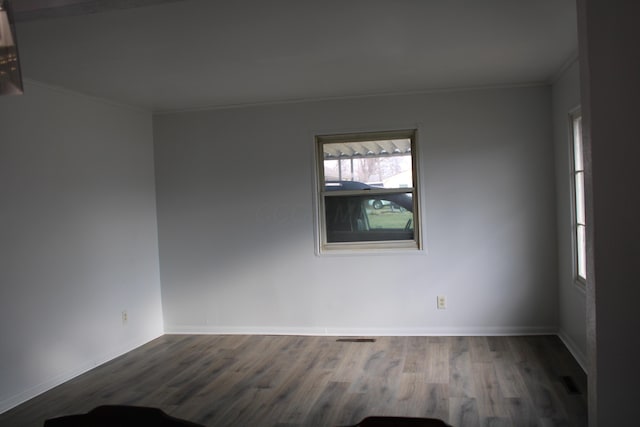 spare room featuring crown molding, baseboards, and wood finished floors