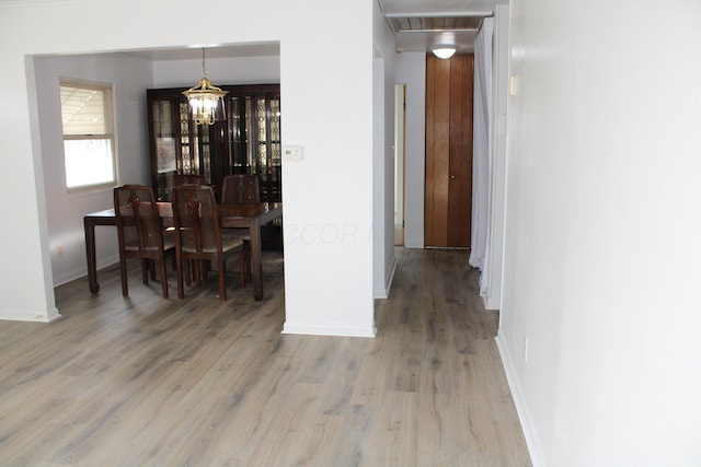 dining space featuring baseboards, visible vents, a chandelier, and wood finished floors