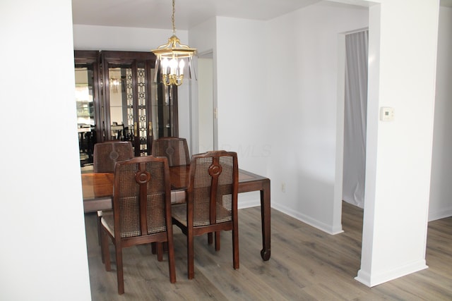 dining room with a notable chandelier, baseboards, and wood finished floors