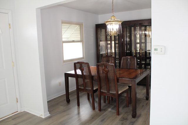 dining area featuring a chandelier, wood finished floors, and baseboards