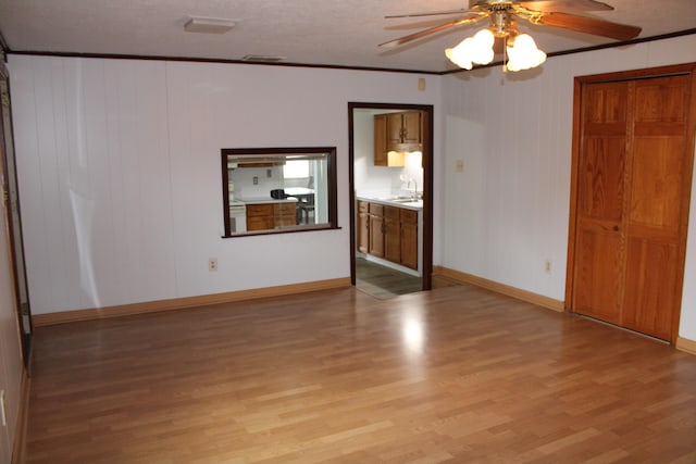 spare room with a sink, visible vents, baseboards, ornamental molding, and light wood finished floors